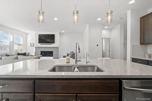 kitchen with dark brown cabinetry, sink, decorative light fixtures, and an island with sink