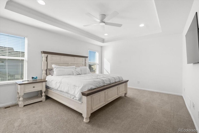 bedroom featuring ceiling fan, a raised ceiling, and light carpet