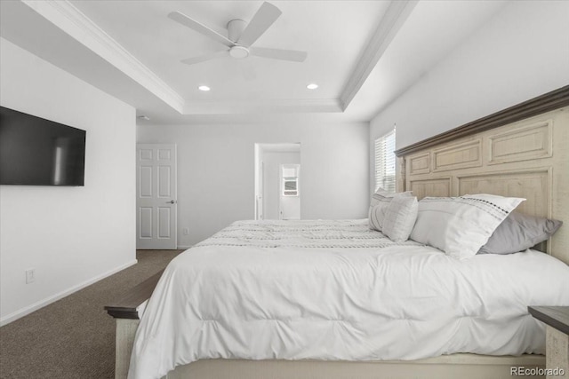 bedroom featuring dark colored carpet, ornamental molding, ceiling fan, and a tray ceiling