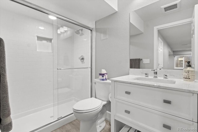 bathroom with visible vents, toilet, a stall shower, wood finished floors, and vanity