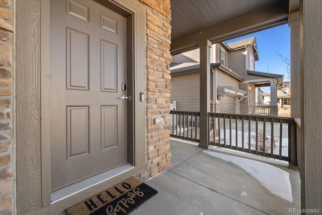 entrance to property featuring brick siding and covered porch