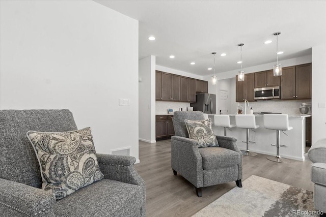 living area with recessed lighting, light wood-style floors, visible vents, and baseboards