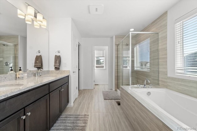 bathroom featuring a shower stall, a garden tub, double vanity, and a sink