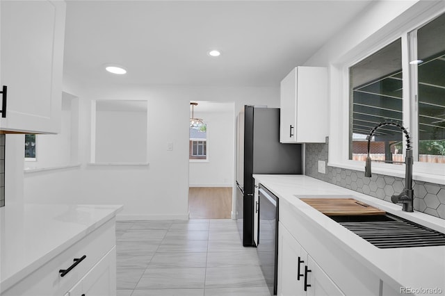 kitchen featuring stainless steel dishwasher, sink, pendant lighting, and white cabinets