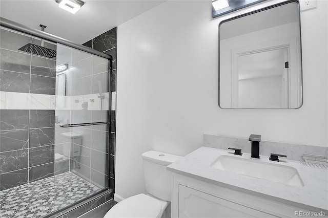 bathroom featuring toilet, a shower with shower door, and vanity