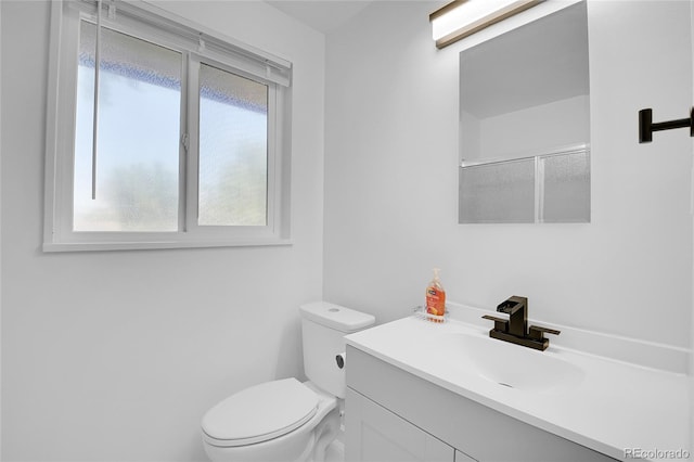 bathroom featuring a shower with shower door, toilet, and vanity