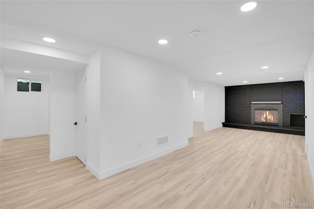 unfurnished living room with a brick fireplace and light hardwood / wood-style floors