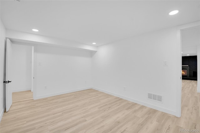 unfurnished room with light wood-type flooring and a fireplace