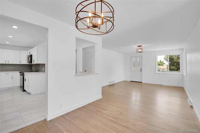 unfurnished living room with light hardwood / wood-style flooring and an inviting chandelier