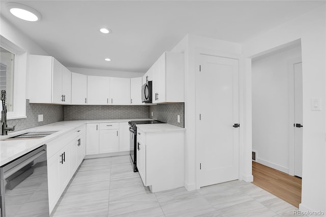 kitchen featuring stainless steel dishwasher, decorative backsplash, sink, range with electric stovetop, and white cabinets