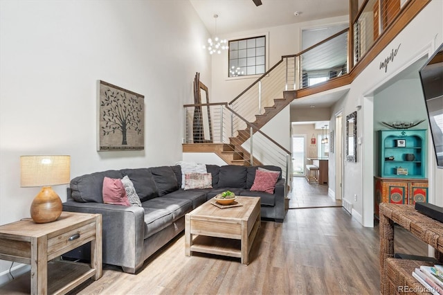 8170 E Phillips Cir, Centennial, CO 80112 - living room featuring stairway, wood finished floors, a high ceiling, a chandelier, and baseboards