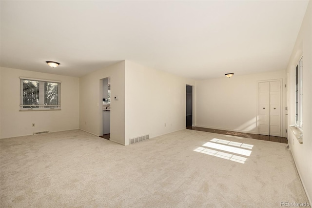 carpeted empty room featuring visible vents