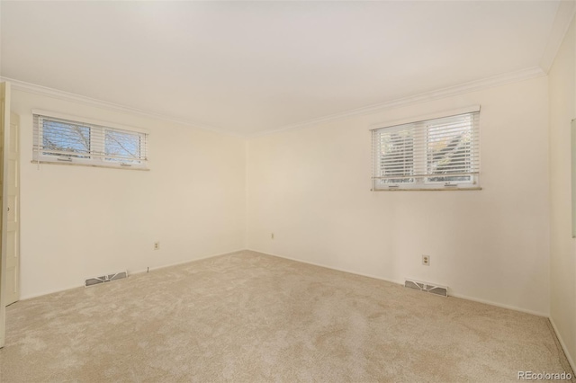 carpeted empty room featuring ornamental molding, visible vents, and plenty of natural light