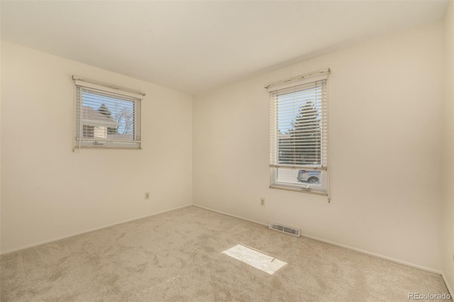 unfurnished room with a wealth of natural light, visible vents, and carpet flooring