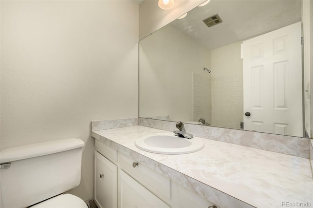 bathroom featuring toilet, walk in shower, vanity, and visible vents