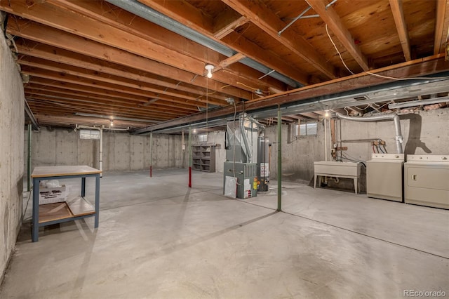 unfinished below grade area with washing machine and dryer, gas water heater, and a sink