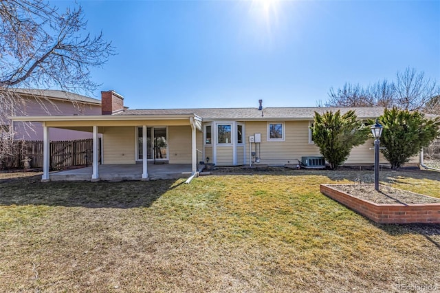 rear view of house with a patio, a chimney, a lawn, central AC unit, and fence