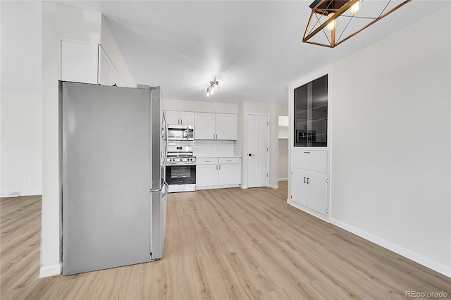 2503-2507 N Taft Ave, Loveland, CO 80538 - kitchen with appliances with stainless steel finishes, light wood-style flooring, white cabinetry, and backsplash