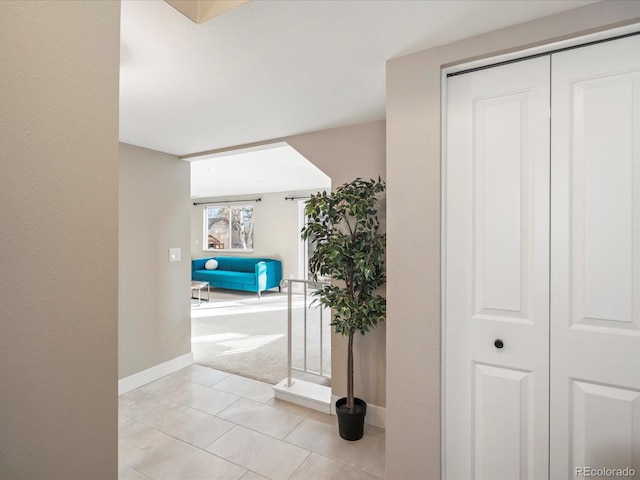 hallway with light tile patterned floors and baseboards