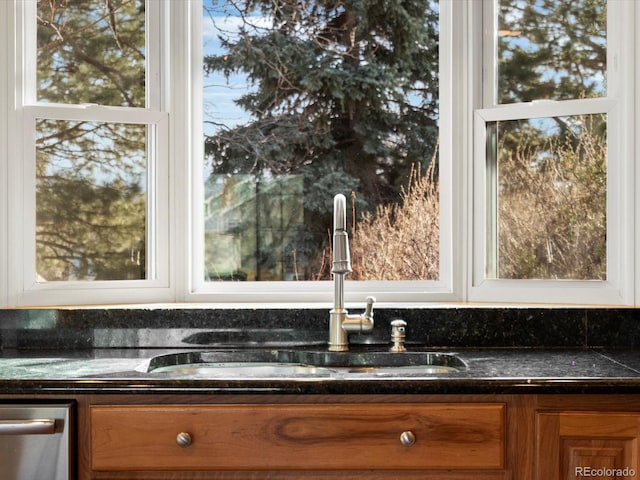 kitchen with brown cabinetry, glass insert cabinets, a sink, and stainless steel dishwasher