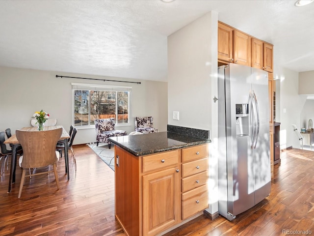 kitchen with dark stone counters, dark wood finished floors, a textured ceiling, and stainless steel fridge with ice dispenser