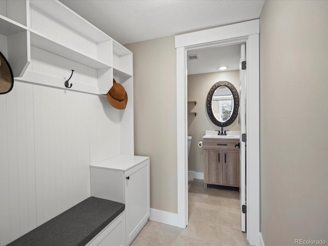 mudroom with light tile patterned floors, baseboards, visible vents, and a sink