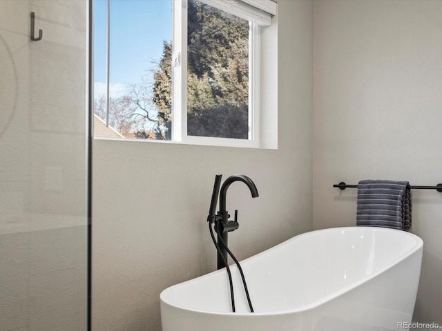 bathroom featuring a sink, a freestanding tub, and a wealth of natural light