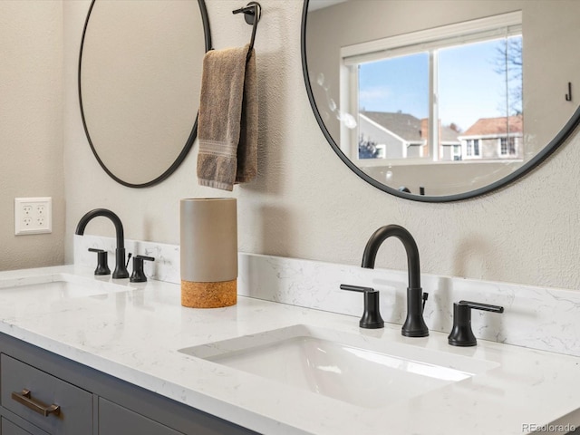 details featuring a textured wall, a sink, and double vanity