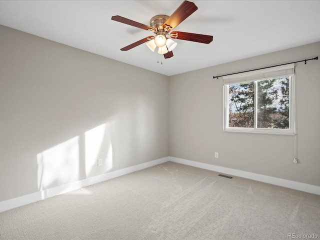 carpeted empty room featuring a ceiling fan, visible vents, and baseboards