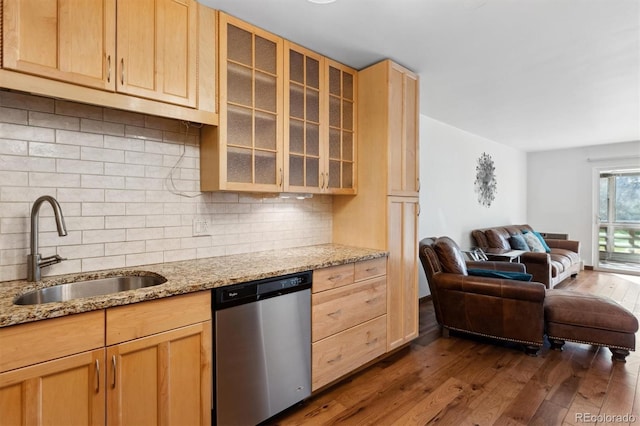 kitchen featuring backsplash, light stone countertops, sink, and stainless steel dishwasher