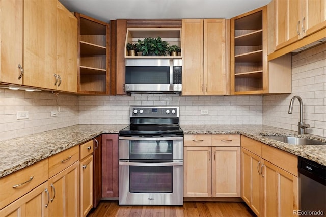 kitchen with appliances with stainless steel finishes, backsplash, light stone counters, and sink