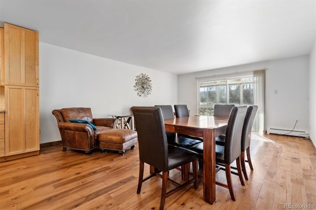 dining area with light hardwood / wood-style floors and a baseboard heating unit