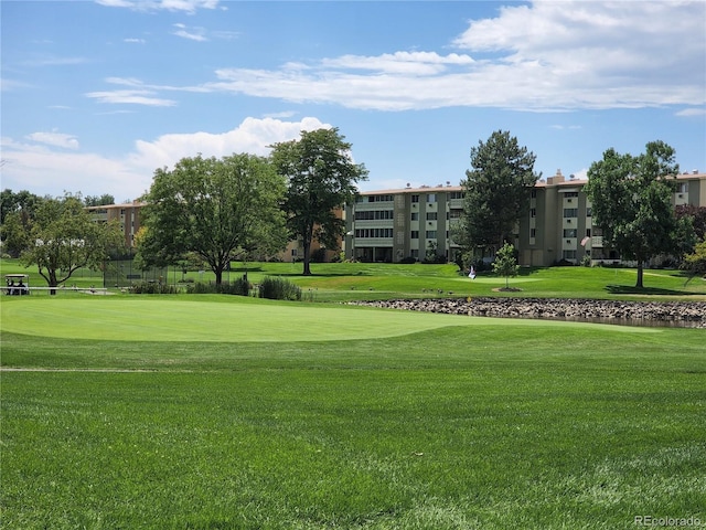 view of community with view of golf course and a yard