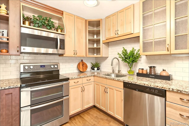 kitchen with a sink, light brown cabinets, open shelves, and stainless steel appliances