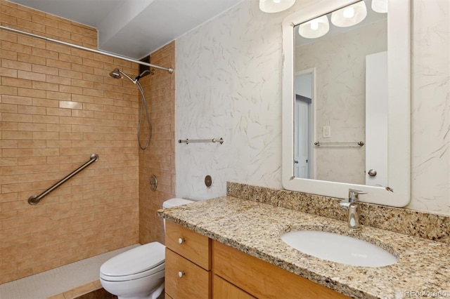 full bathroom with vanity, a tile shower, and toilet