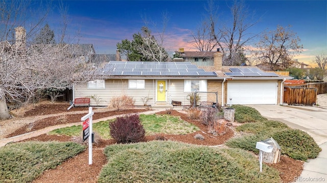 7727 W 81st Pl, Arvada, CO 80005 - view of front facade featuring roof mounted solar panels, an attached garage, concrete driveway, and a chimney
