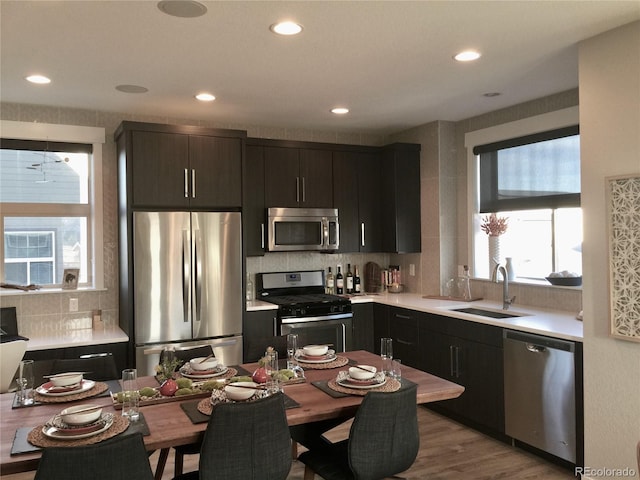 kitchen featuring appliances with stainless steel finishes, tasteful backsplash, a sink, light countertops, and recessed lighting