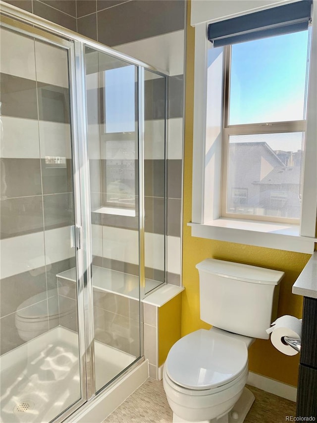 full bathroom featuring baseboards, a stall shower, and toilet