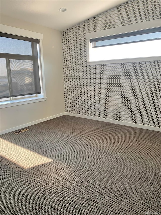 carpeted empty room featuring baseboards and visible vents