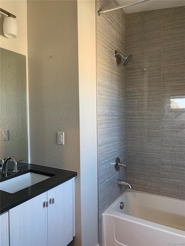 full bathroom featuring vanity, a textured wall, and bathtub / shower combination
