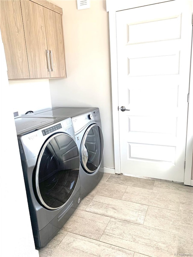 clothes washing area with washing machine and clothes dryer, visible vents, and cabinet space