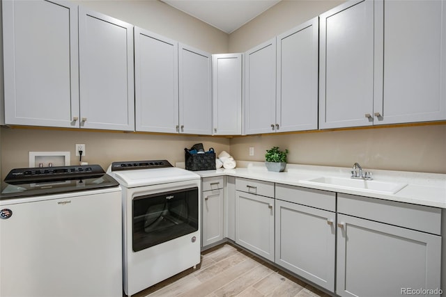 washroom featuring separate washer and dryer, cabinets, sink, and light hardwood / wood-style floors