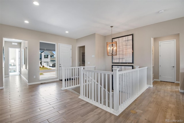 hall with light hardwood / wood-style flooring and an inviting chandelier