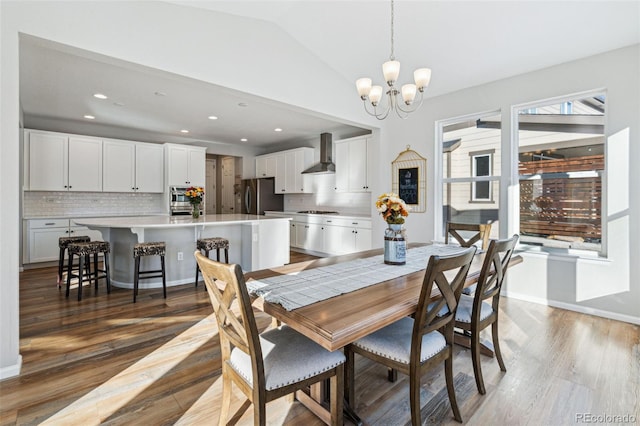 dining area with vaulted ceiling, hardwood / wood-style floors, and a notable chandelier