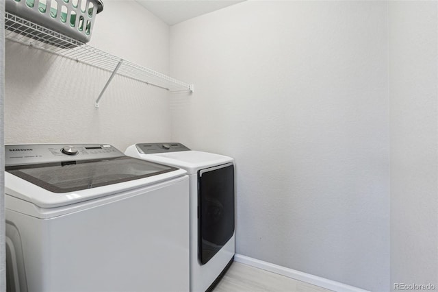 clothes washing area with independent washer and dryer and light hardwood / wood-style flooring