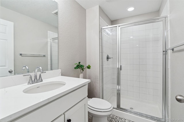 bathroom featuring vanity, a shower with shower door, and toilet