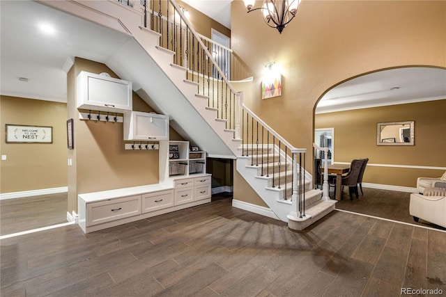 staircase featuring arched walkways, baseboards, and wood finished floors