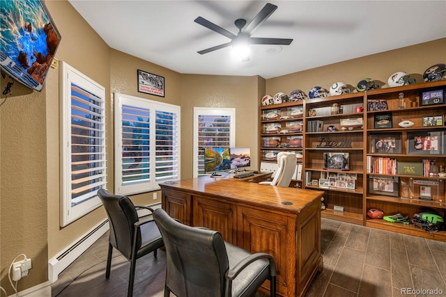 home office featuring a ceiling fan, a textured wall, a baseboard heating unit, and dark wood-type flooring