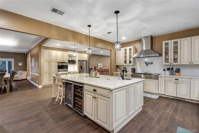kitchen with appliances with stainless steel finishes, wine cooler, wall chimney range hood, and tasteful backsplash