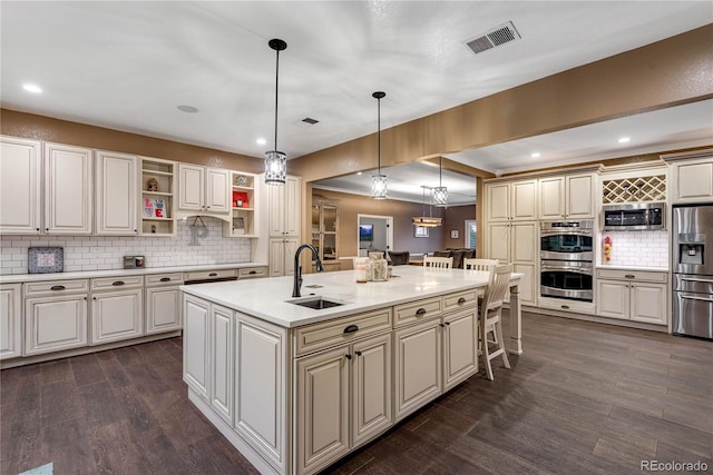 kitchen with appliances with stainless steel finishes, a sink, light countertops, backsplash, and visible vents